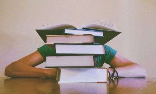 Student with stack of books in front